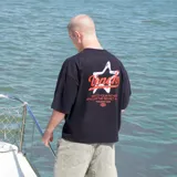 Remera negra de algodón con efecto gastado, corte oversize y estampado en la espalda con una estrella y la palabra "Venefo" en rojo.