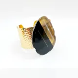 Pulsera dorada tipo brazalete con textura martillada y dije de piedra ágata azul y verde.