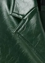 Abrigo largo de efecto piel en color verde oscuro, con cuello de solapa, cierre frontal con botones, manga larga y bolsillos laterales con solapa.