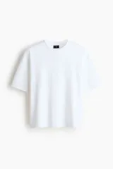 Remera blanca boxy de punto liviano de algodón, con hombros caídos, cuello redondo acanalado y corte oversized.