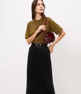 Pollera midi de corte lápiz en poliuretano (PU) color marrón oscuro, de tiro alto, con recorte frontal, abertura trasera y pasadores para cinto. Incluye un cinto ancho ajustable con hebilla metálica rectangular.