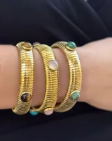 Pulsera estilo vintage de acero dorado, con diseño de eslabones estriados y apliques de piedras naturales oscuras.