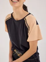 Remera blanca de algodón suave con detalle de bordado en los hombros y cordón ajustable en el ruedo.