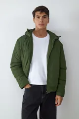 Campera acolchada color verde militar, con capucha integrada, cierre frontal de cremallera y mangas largas. Diseño funcional y versátil para uso diario.