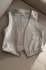 Chaleco clásico plateado de cuero ovino, con cuello en V y sin cierre.