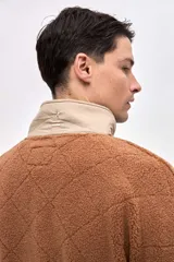 Buzo de sherpa con textura capitoneada, diseño de medio cierre y cuello alto en color beige contrastante. Presenta un calce holgado, mangas largas con puños elásticos y bolsillos laterales.