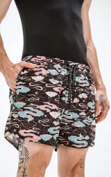 Short de baño de microfibra de secado rápido, color negro con estampado de nubes en tonos pastel (rosa, celeste y blanco). Incluye malla interna, cordón ajustable en la cintura con logo de la marca y un bolsillo trasero.