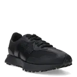 Championes urbanos New Balance modelo 327, color negro, confeccionados en una combinación de malla y material sintético. Presentan el logo 'N' característico en el lateral, cordones al tono y una suela de goma con relieve que se extiende hacia el talón.