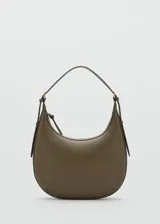 Bolso de hombro tipo hobo con diseño curvo y minimalista. Presenta un asa ajustable con hebillas laterales y cierre superior de cremallera.