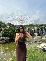 Vestido largo de microtul color marrón, con escote buche y cuello halter regulable. Presenta un diseño ajustado al cuerpo con forro interno corto.