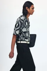 Pantalón sastrero de sarga en color negro, con corte holgado, piernas amplias con raya marcada, cierre frontal con botón y corchete ocultos, bolsillos al bies y bolsillos traseros insertados.