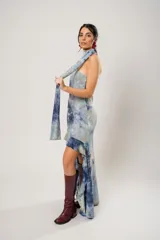 Vestido corto con estampado abstracto en tonos azules y beige. Presenta escote halter con pañuelo al cuello, corte irregular y ruedo con volados.