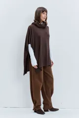 Poncho asimétrico de tejido de punto en color marrón, con cuello alto tipo polera y diseño sin mangas con aberturas laterales.