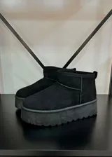 Botas cortas de gamuza color tostado con plataforma plana y suela dentada. Presentan un diseño minimalista con costuras reforzadas y forro interior de peluche.