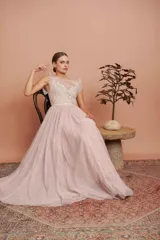 Vestido largo de tul plumetí en color rosa suave, con detalles de encaje bordado en el torso y volados en los hombros.
