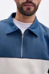 Buzo deportivo de hombre con medio cierre, cuello polo y diseño de bloques de color en azul, beige y marrón.