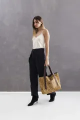 Cartera tipo tote bag de gran tamaño, confeccionada en cuero con estampado animal print de leopardo. Presenta manijas, detalles y terminaciones en cuero color chocolate. Incluye cierre metálico superior para mayor seguridad y bolsillo externo.