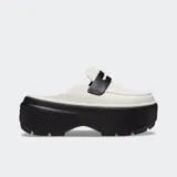 Mocasín Crocs Stomp Loafer color blanco hueso con suela de plataforma negra exagerada y ligera. Presenta una correa decorativa negra con el logo de Crocs en la parte superior.