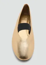 Zapato plano tipo bailarina en color dorado, con punta redonda y tira elástica en color negro sobre el empeine.