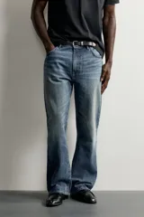 Jeans flare fit de denim negro, tiro medio, ajustados arriba y con botamanga acampanada. Cuentan con cinco bolsillos, lavado efecto gastado y bajo con acabado irregular. Cierre frontal con cremallera y botón.