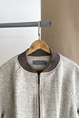 Campera estilo bomber color beige con textura, cierre delantero, cuello, puños y ruedo tejidos. Forrada, confeccionada en lana fina sin teñir.