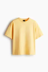 Remera de manga corta color amarillo pálido, confeccionada en punto de algodón pesado, con cuello redondo ribeteado y hombros caídos, de corte holgado.