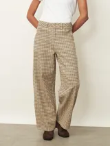 Pantalón tipo jean de corte recto y tiro medio, con estampado de cuadros en tonos beige y marrón. Cuenta con cierre frontal, bolsillos laterales y trabillas para cinturón.