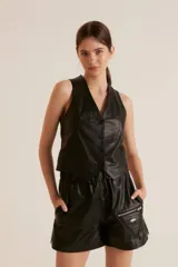 Short negro de cuero con cintura elastizada, bolsillos laterales y un bolsillo con cierre en la pierna derecha.