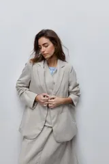 Blazer beige de corte recto, con solapa clásica, bolsillos frontales con solapa y cierre de un botón.