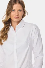 Camisa de tejido Oxford lisa y color blanco, con cuello camisero, cierre frontal de botones y mangas largas con puños abotonados.