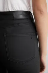 Pantalón de corte oxford con acabado engomado, tiro alto y cierre frontal con botón y cremallera.