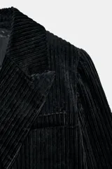 Abrigo largo de Zara confeccionado en tejido de pana con textura acanalada. Presenta un diseño de corte recto, cuello con solapas, cierre frontal cruzado con botones y bolsillos delanteros. Incluye forro interior a tono.