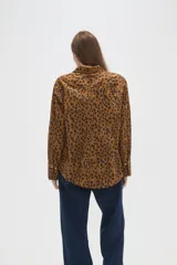 Camisa de algodón con estampado de manchas oscuras sobre fondo tostado, de corte holgado, manga larga, cuello clásico y cierre frontal con botones.