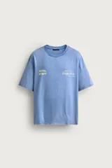 Camiseta relaxed fit de color celeste con efecto acid wash, cuello redondo y manga corta. Cuenta con estampa frontal con la inscripción "HOTEL STAFF" y "Escape Ibiza" en tonos amarillos.