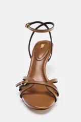 Sandalia de tacón fino color marrón, con tiras finas cruzadas en la parte delantera y tira ajustable con hebilla en el tobillo.