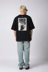 Remera color crudo, corte oversize, mangas cortas y cuello redondo. Estampado frontal con dos árboles unidos por sus raíces y parche estampado en la espalda con una silueta de mano que se fusiona con ramas.