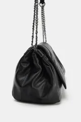 Bolso bandolera de hombro en color negro, con diseño de costuras horizontales y verticales. Cuenta con una cadena metálica plateada que funciona como correa y un asa de mano superior. El cierre es mediante botón imantado.