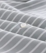 Camisa de corte regular confeccionada en una mezcla de bambú y poliéster, con diseño de rayas verticales en tono verde claro y blanco. Presenta cuello inglés, cierre frontal con botones y mangas largas con puños ajustables.