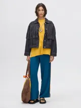 Campera de denim color marrón con cuello camisero, cierre frontal con botones y flecos en la parte superior de la espalda.