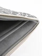 Funda para notebook gris con estampado de hojas en blanco y cierre con cremallera.