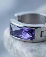 Aros tipo argolla de acero con diseño de medio aro y detalle de circonia color violeta en el centro.