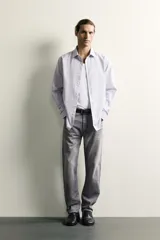 Jeans regular fit de mezclilla negra con efecto lavado, corte recto y tiro medio. Cuenta con diseño de cinco bolsillos y cierre frontal con cremallera y botón.