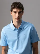 Chomba de manga corta Calvin Klein confeccionada en algodón interlock, con cuello clásico y cierre frontal de botones. Presenta un diseño liso en color celeste con el logo de la marca bordado sutilmente en el pecho.