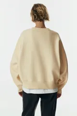 Buzo oversized de cuello redondo con hombros caídos, confeccionado con interior cepillado suave. Presenta puños y bajo en punto acanalado.