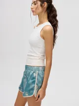 Short de estilo deportivo con pretina elástica, confeccionado en tela satinada con estampado tipo tie-dye en tonos azul y blanco. Presenta bordes con vivo en color crema y un pequeño logo bordado en la parte inferior.