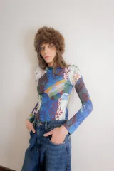 Remera de manga larga confeccionada en algodón elastizado con estampado multicolor de estilo collage que combina paisajes, motivos florales y patrones geométricos.