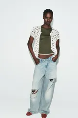 Camiseta de corte slim fit, color verde militar, con cuello redondo y manga corta. Presenta vivos de contraste blancos en el ruedo de las mangas y en el bajo.