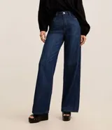 Pantalón de jean de corte wide leg, tiro alto, con bolsillos delanteros y traseros, trabillas para cinturón y cierre frontal con cremallera y botón.