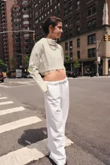Camisa corta de manga larga con cuello solapa y cierre frontal de botones. Presenta un tejido con efecto arrugado y un diseño con forro interior semitransparente que sobresale en el ruedo.