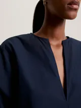 Camisa azul marino de algodón con cuello en V y mangas largas acampanadas.